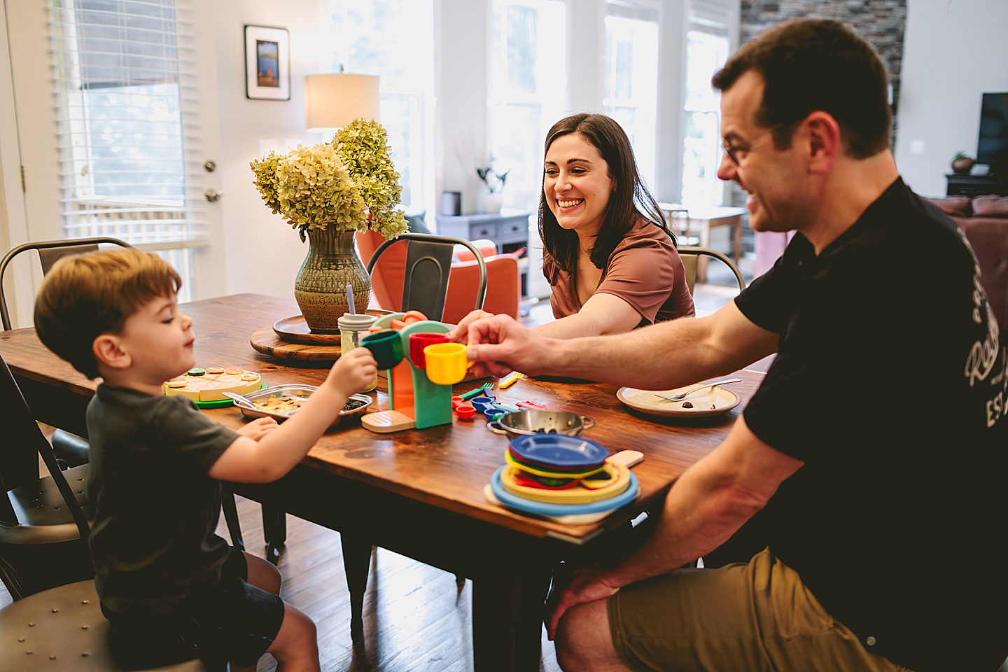 Toddler using play kitchen to make pizza for his family