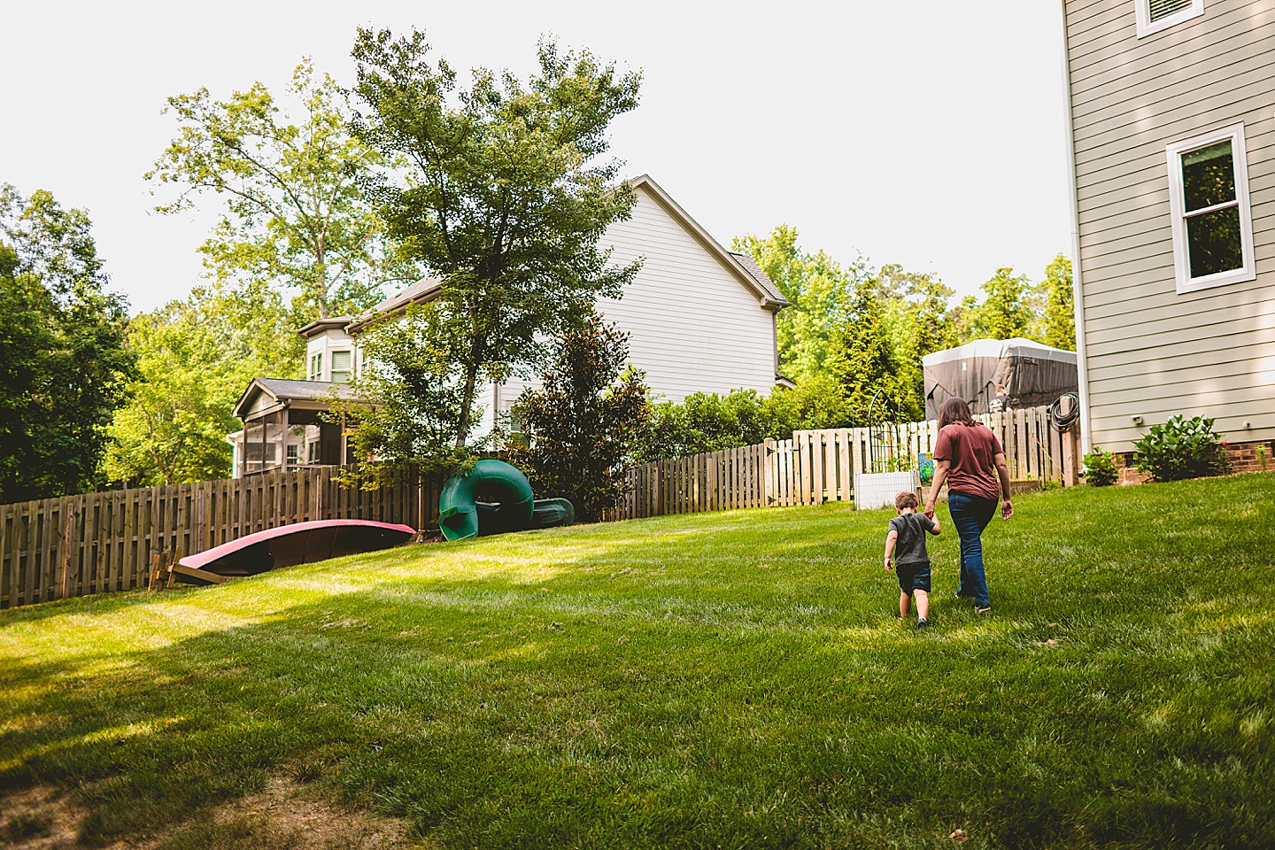 Child walking with his mom through the backyard