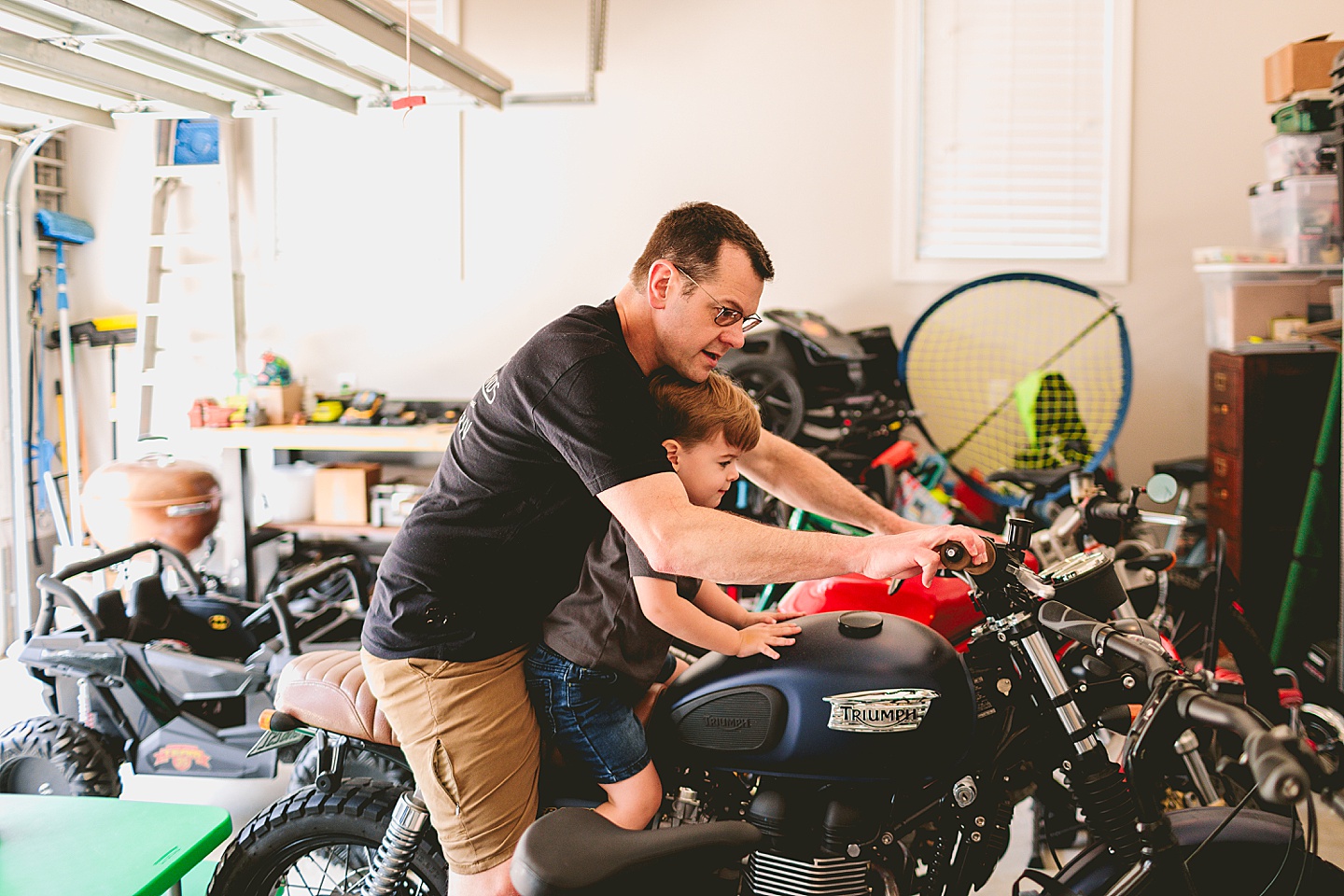 Child sitting on motorcycle with his dad