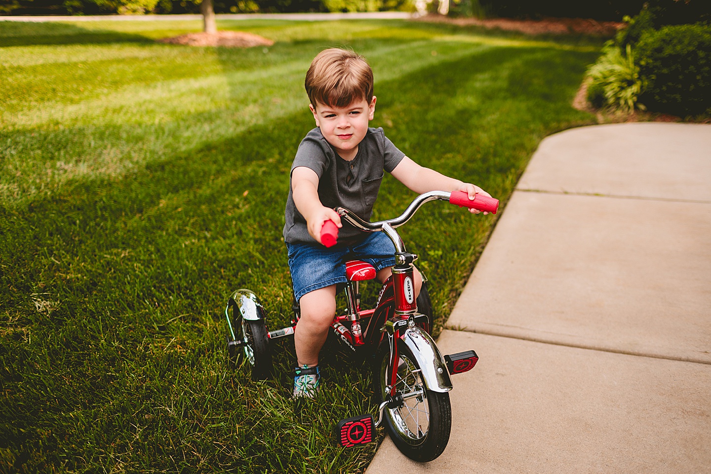 Child riding a tricycle through yard