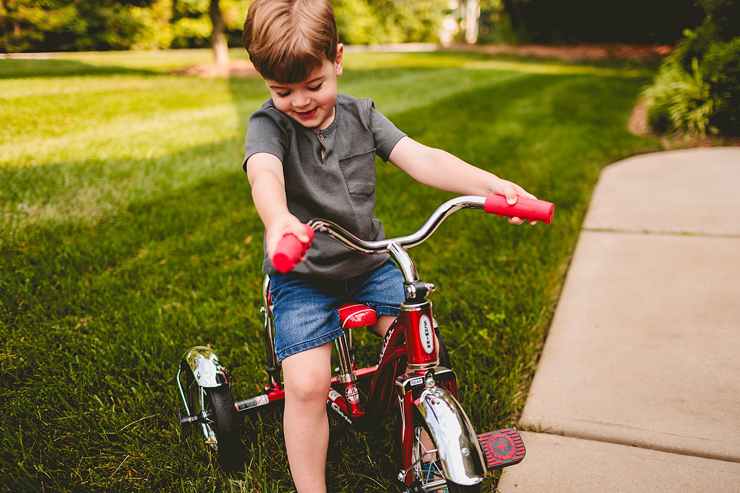 Child riding a tricycle through yard