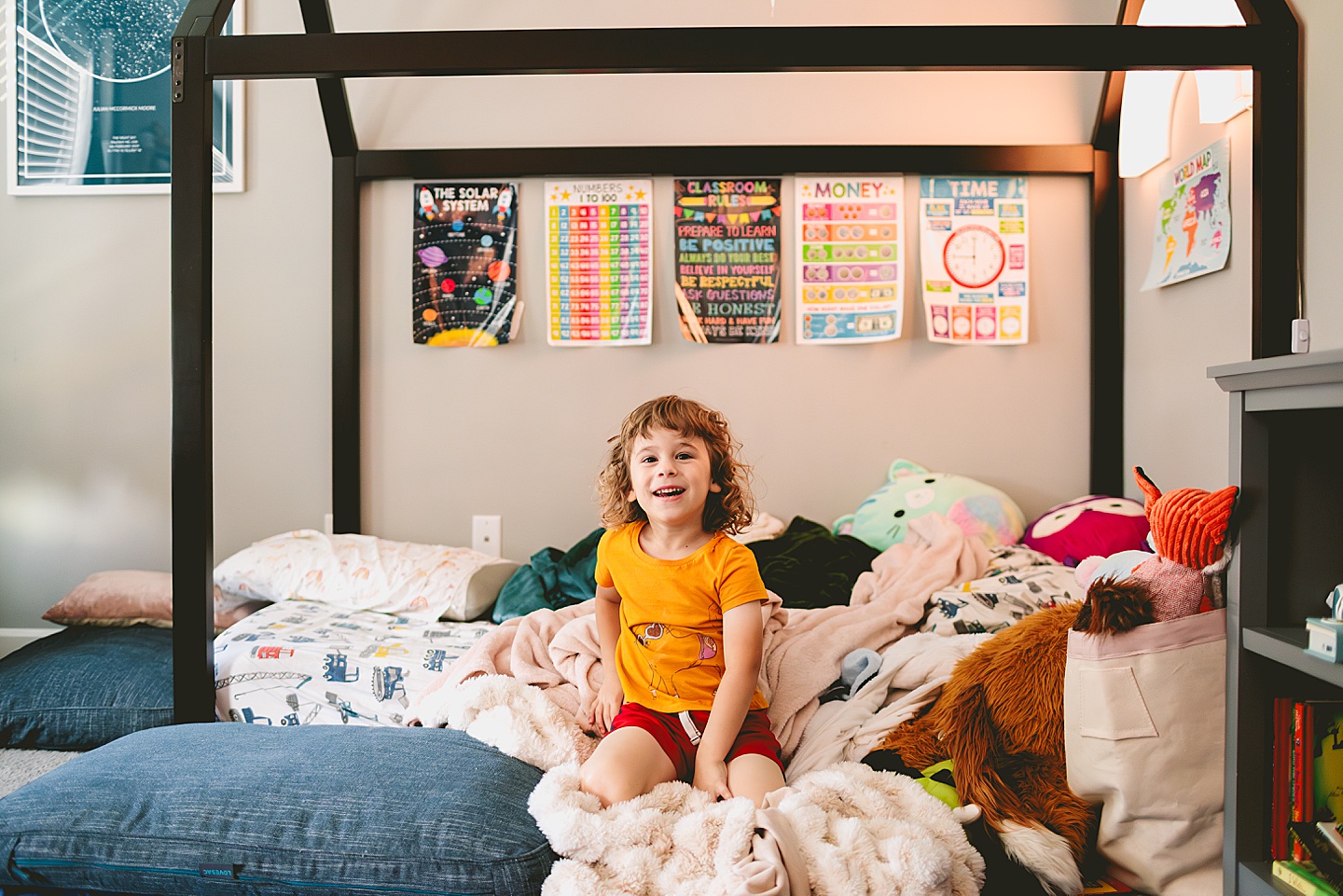 Child in his room surrounded by stuffed animals