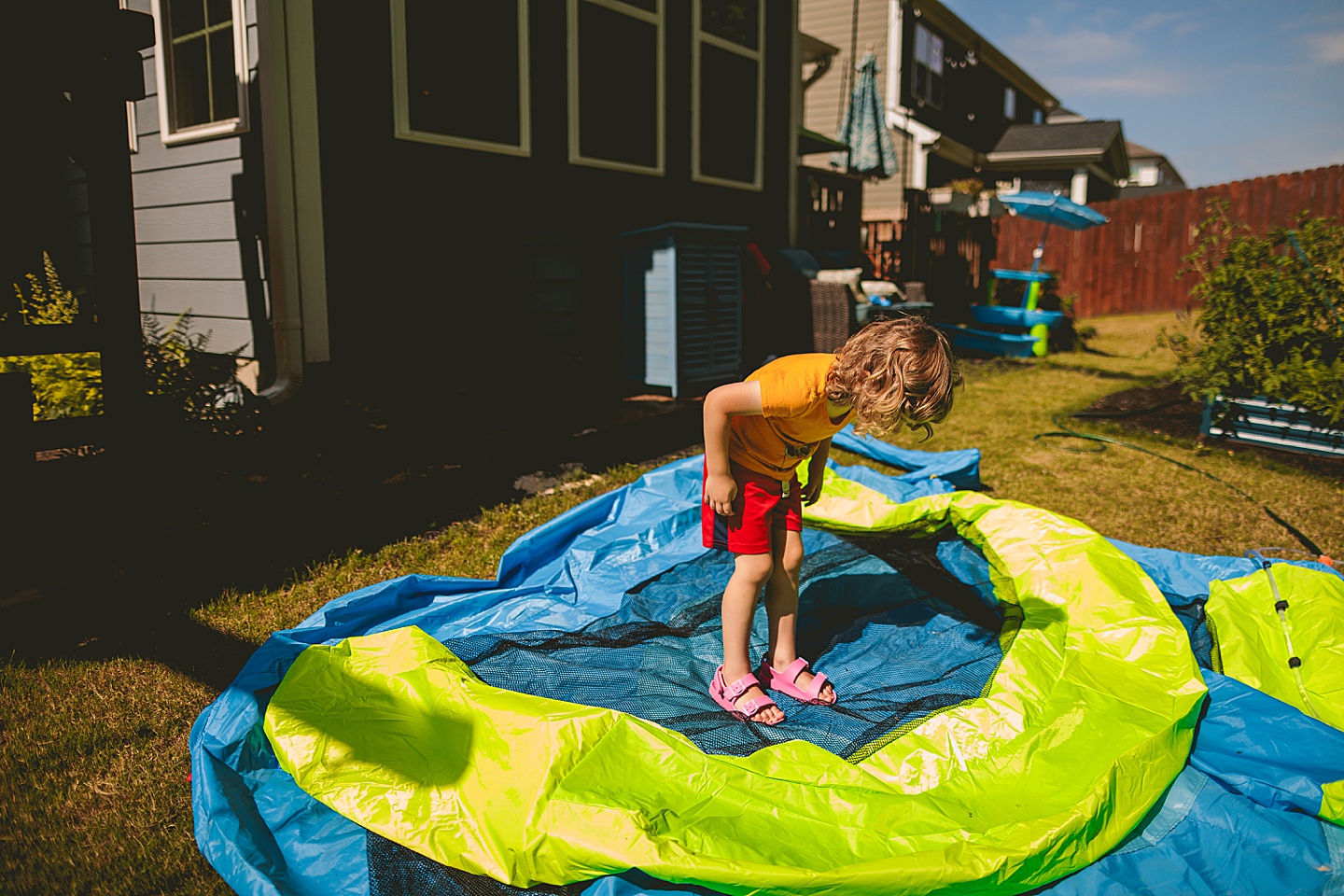 Boy jumping on deflated bounce house in backyard