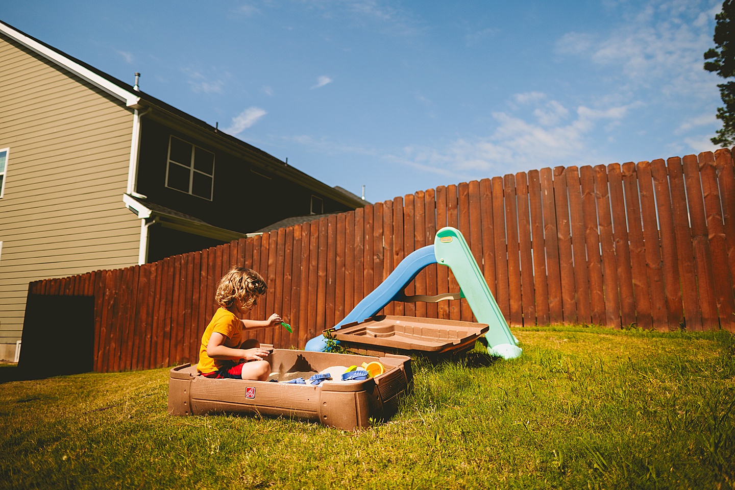 Child playing in sandbox in backyard