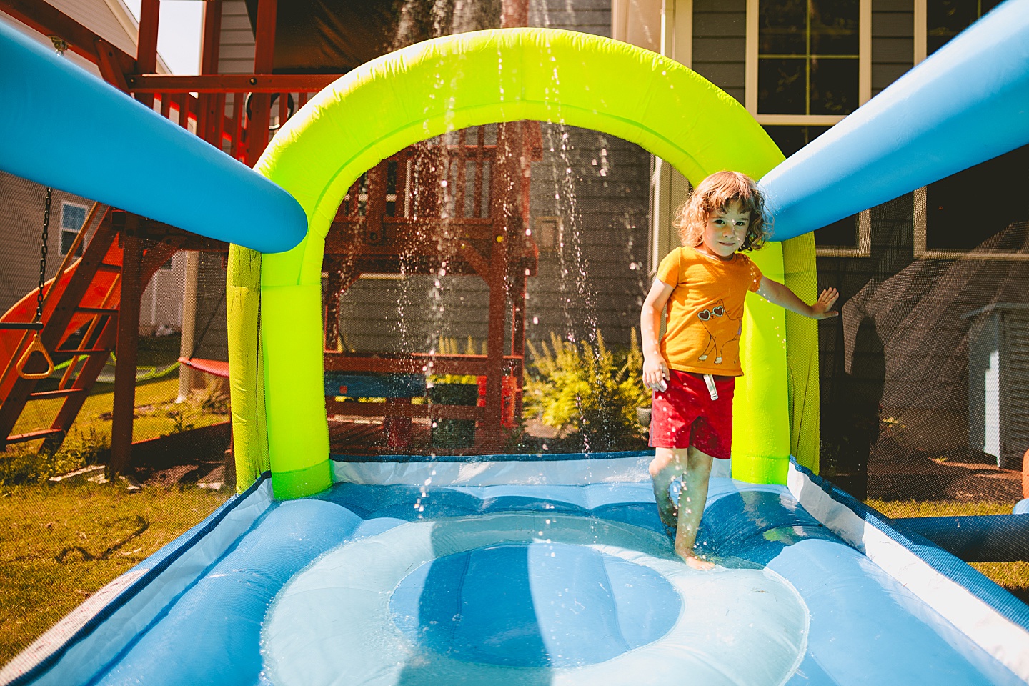 Kid playing in sprinkler bounce house