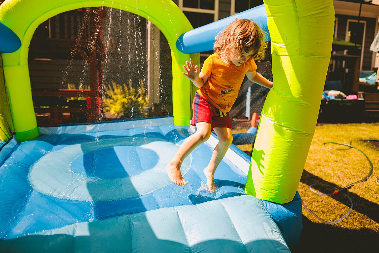 Kid playing in sprinkler bounce house