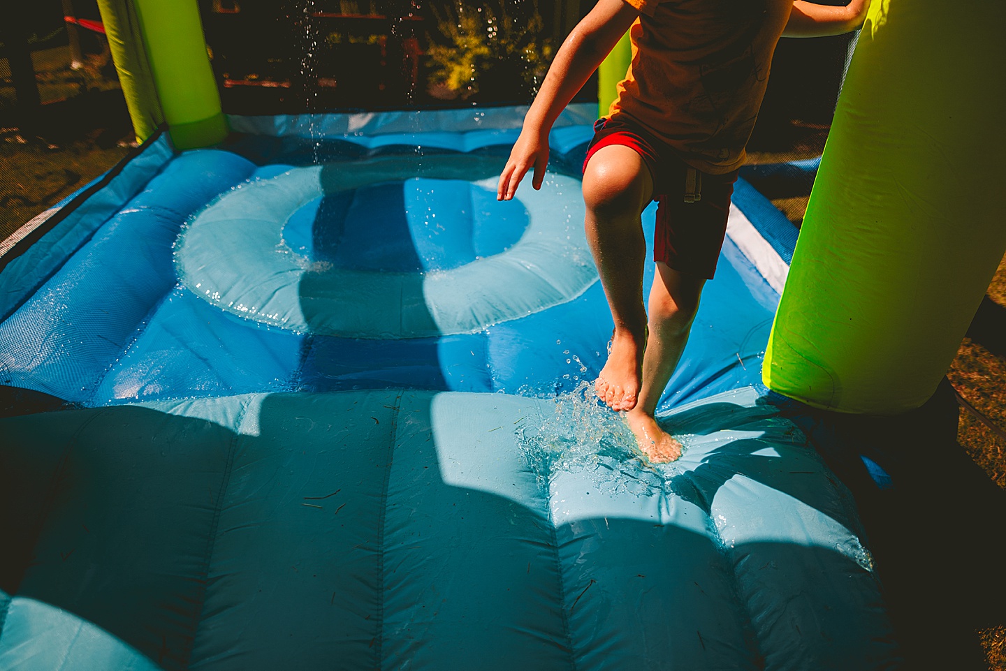 Kid playing in sprinkler bounce house