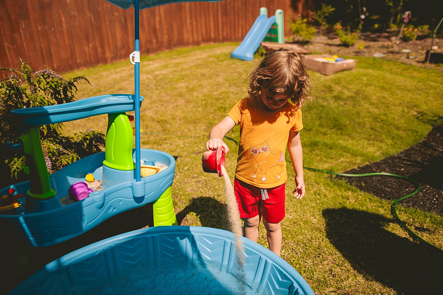 Child pouring sand into a swimming pool