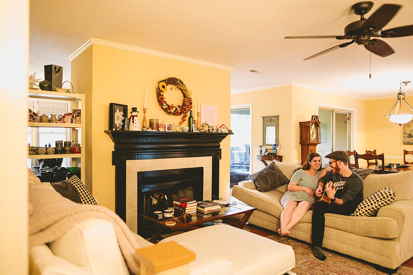Couple sitting in living room on couch playing guitar