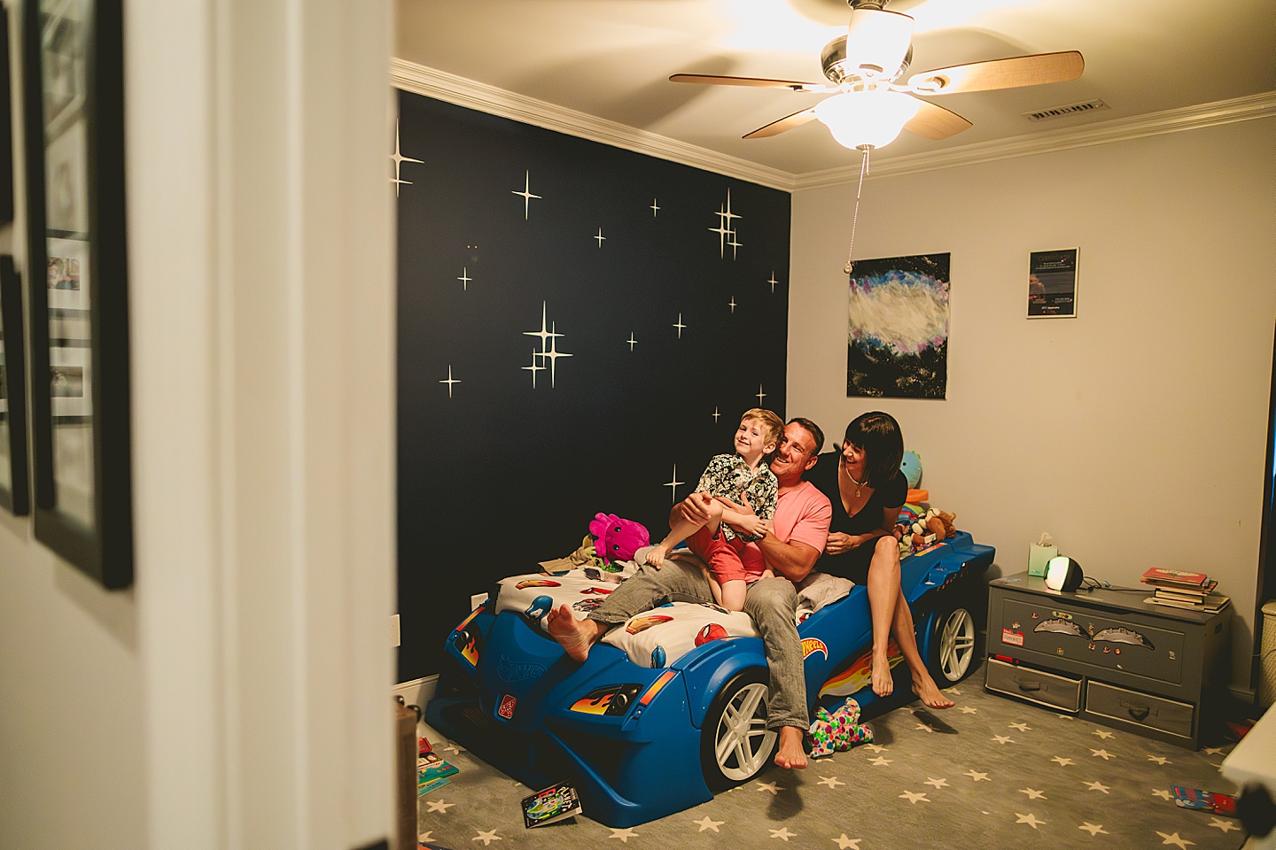 Boy hanging out with his parents on his race car bed