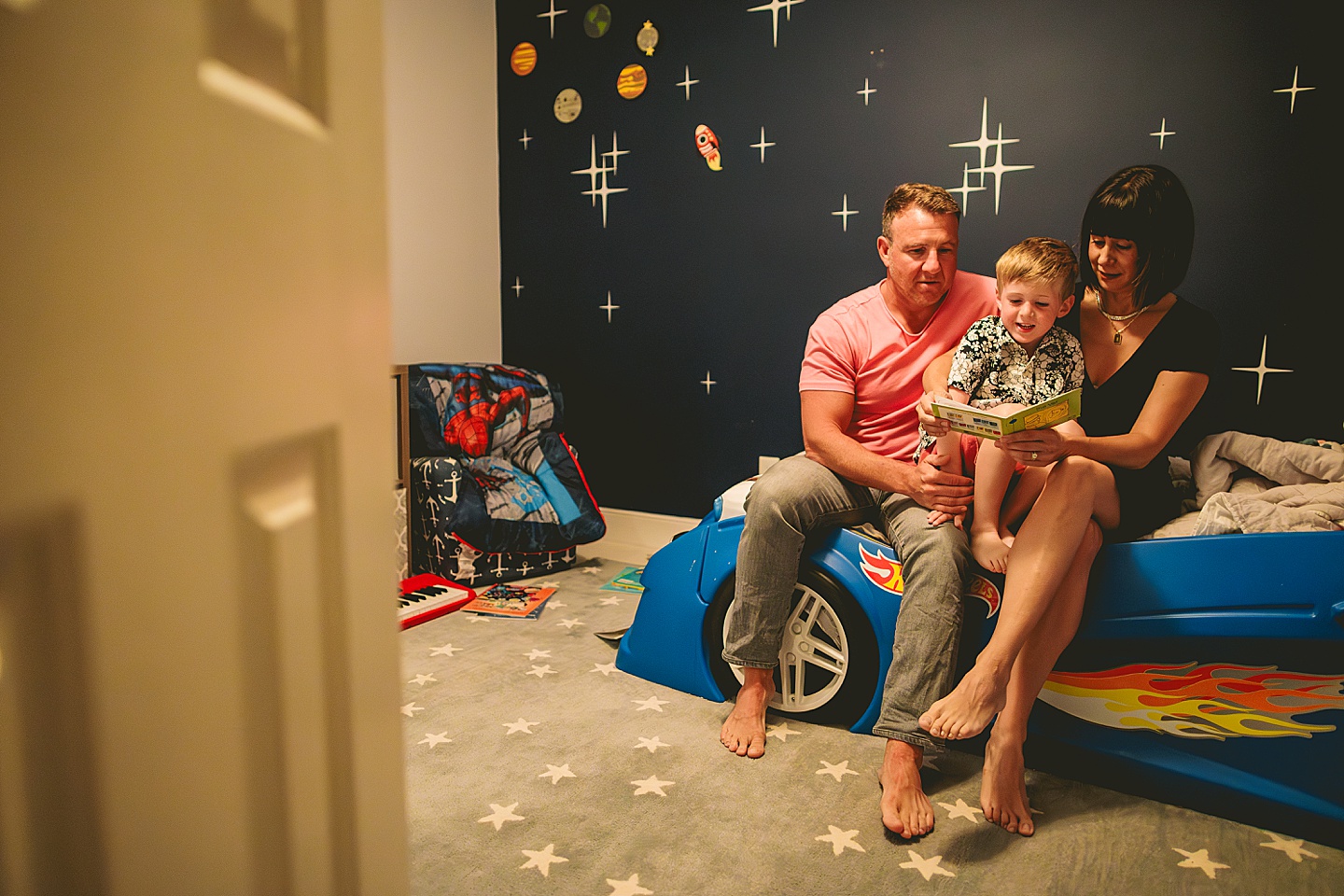 Boy sitting on bed with his parents reading a book