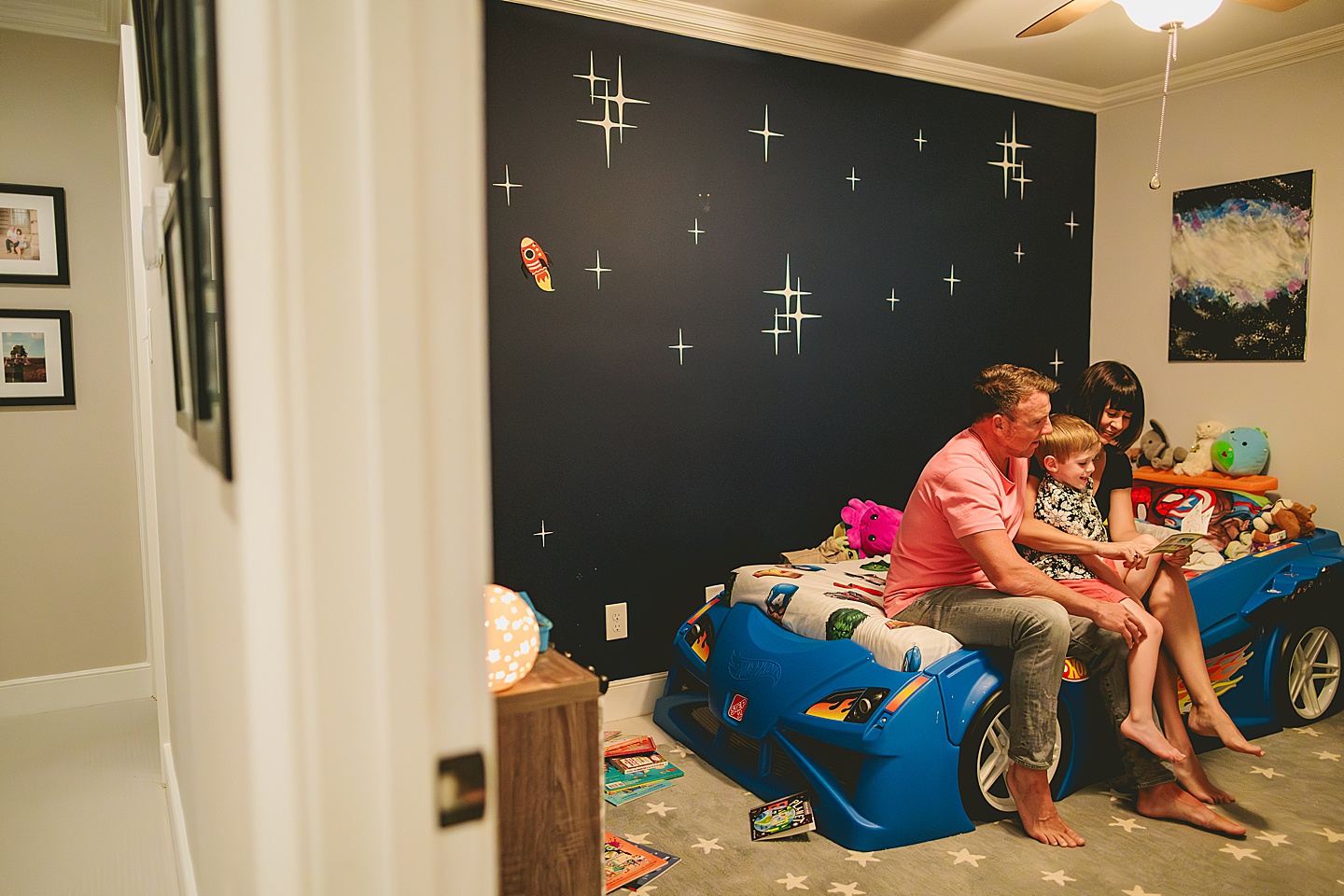 Boy sitting on bed with his parents reading a book