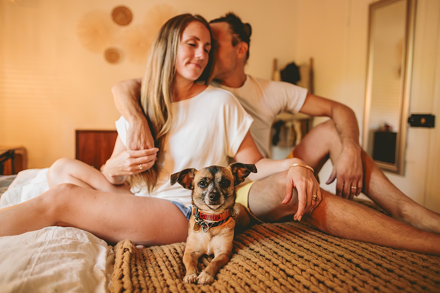 Couple sitting on bed with their dog