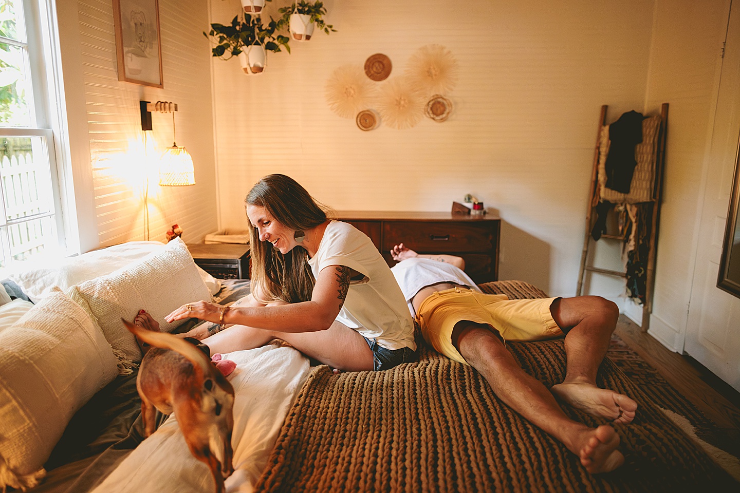 Couple sitting on bed with their dog