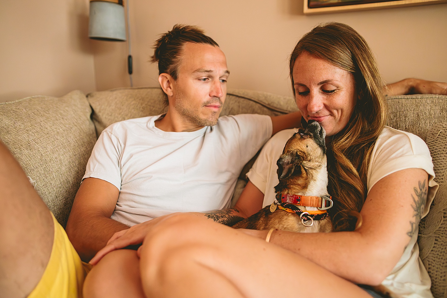 Couple sitting on their couch holding their small dog