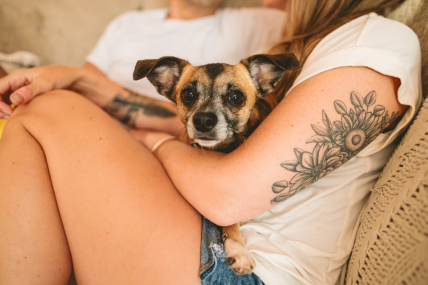 Couple sitting on their couch holding their small dog