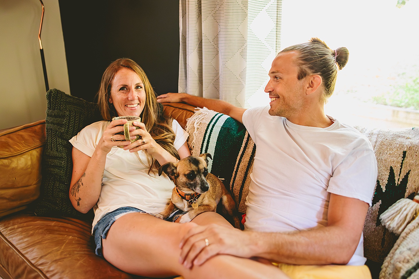Couple sitting on couch with small dog at home in Hillsborough
