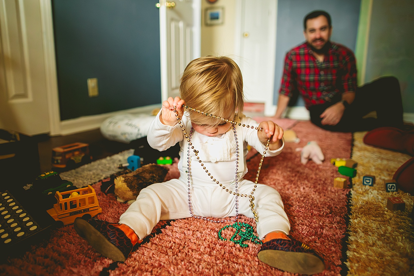 Toddler putting on Mardi Gras beads