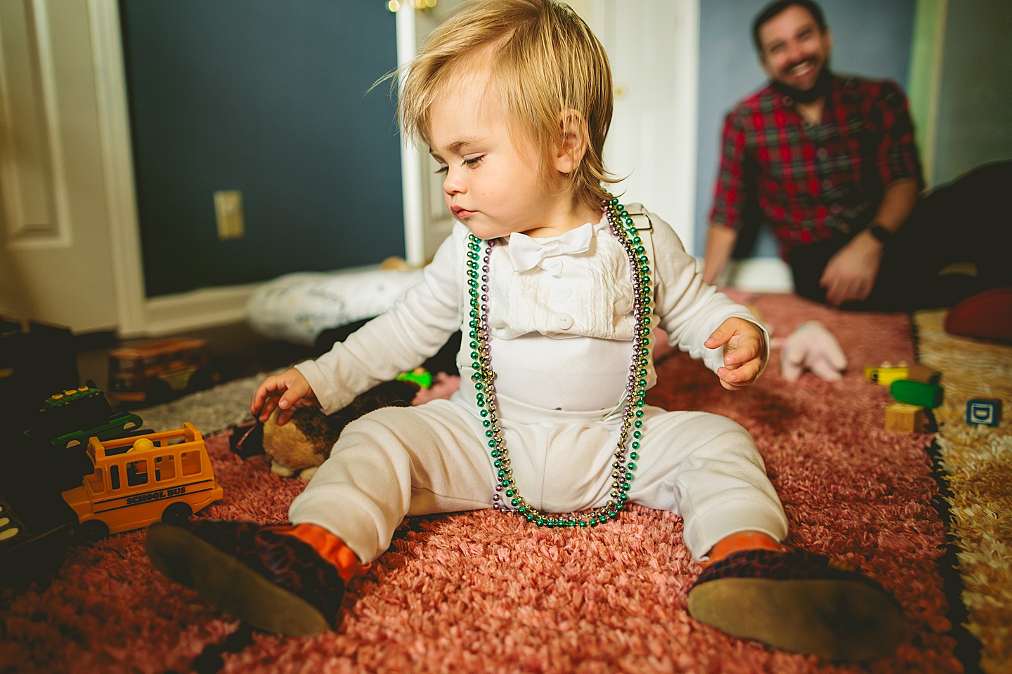 Toddler putting on Mardi Gras beads