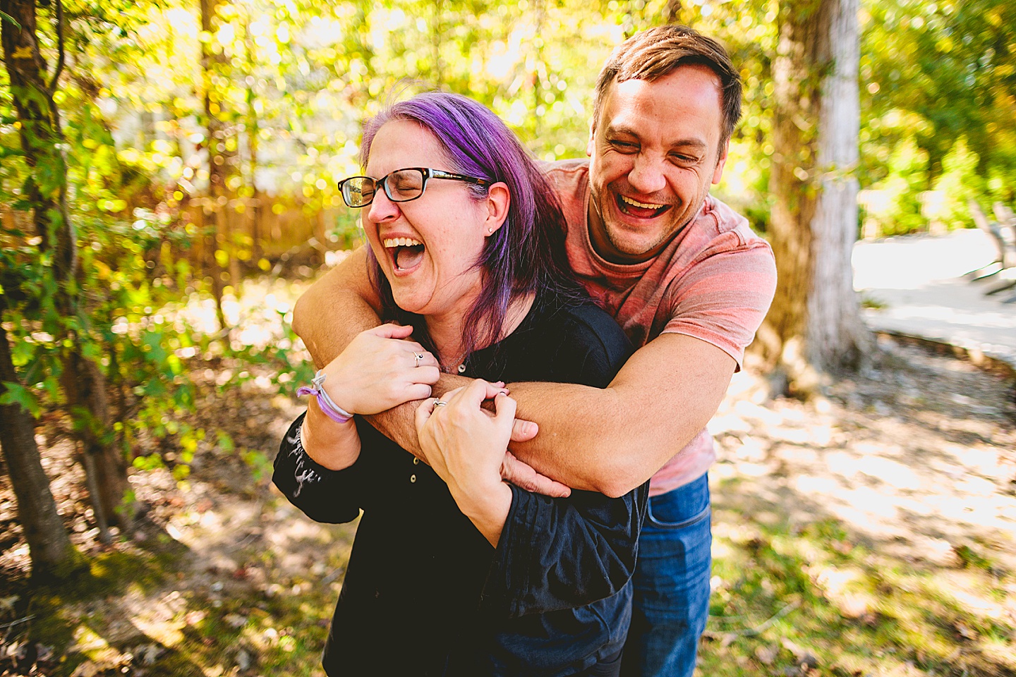 Parents laughing outside in a yard in Holly Springs while hugging