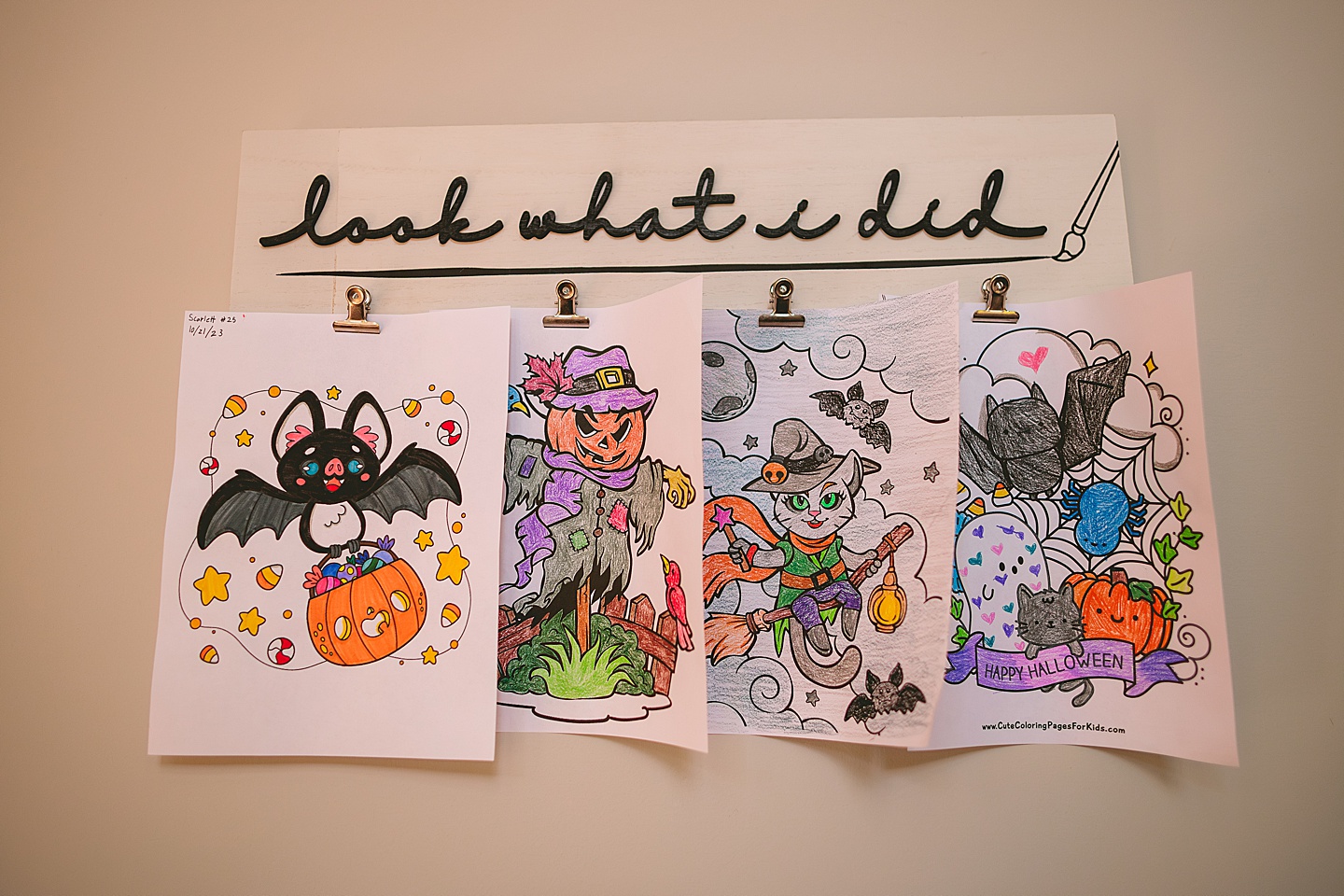 A collection of colored Halloween artwork hangs on a wall