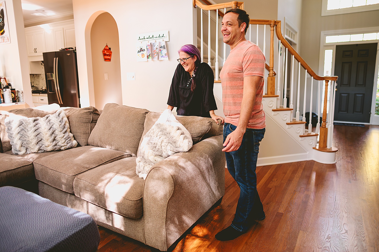 Parents stand by a couch and laugh