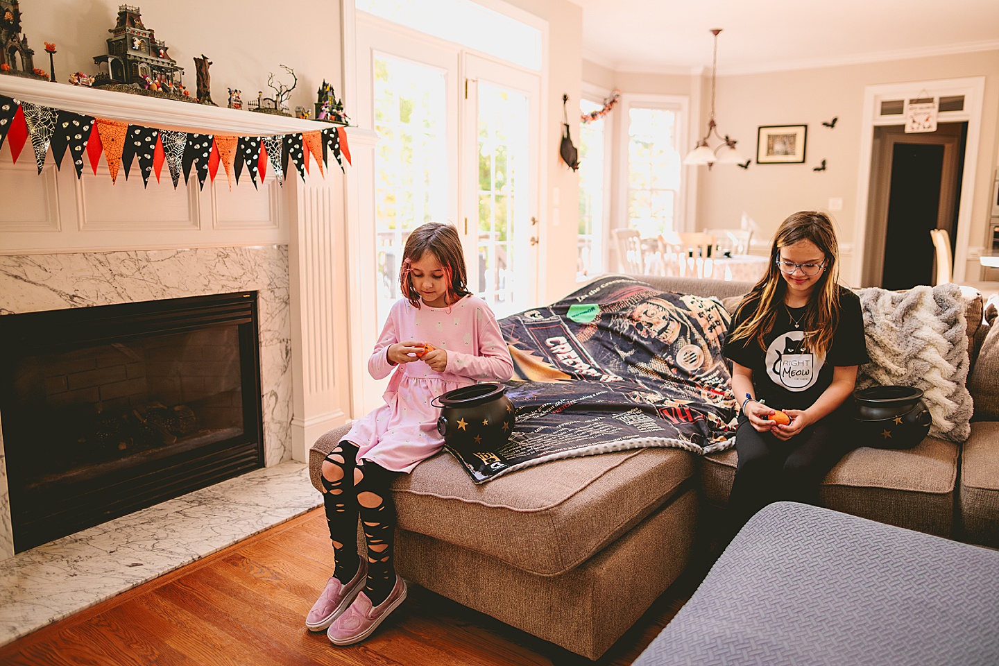 Sisters sit on a couch and open up orange Halloween eggs to see what they got after their hunt