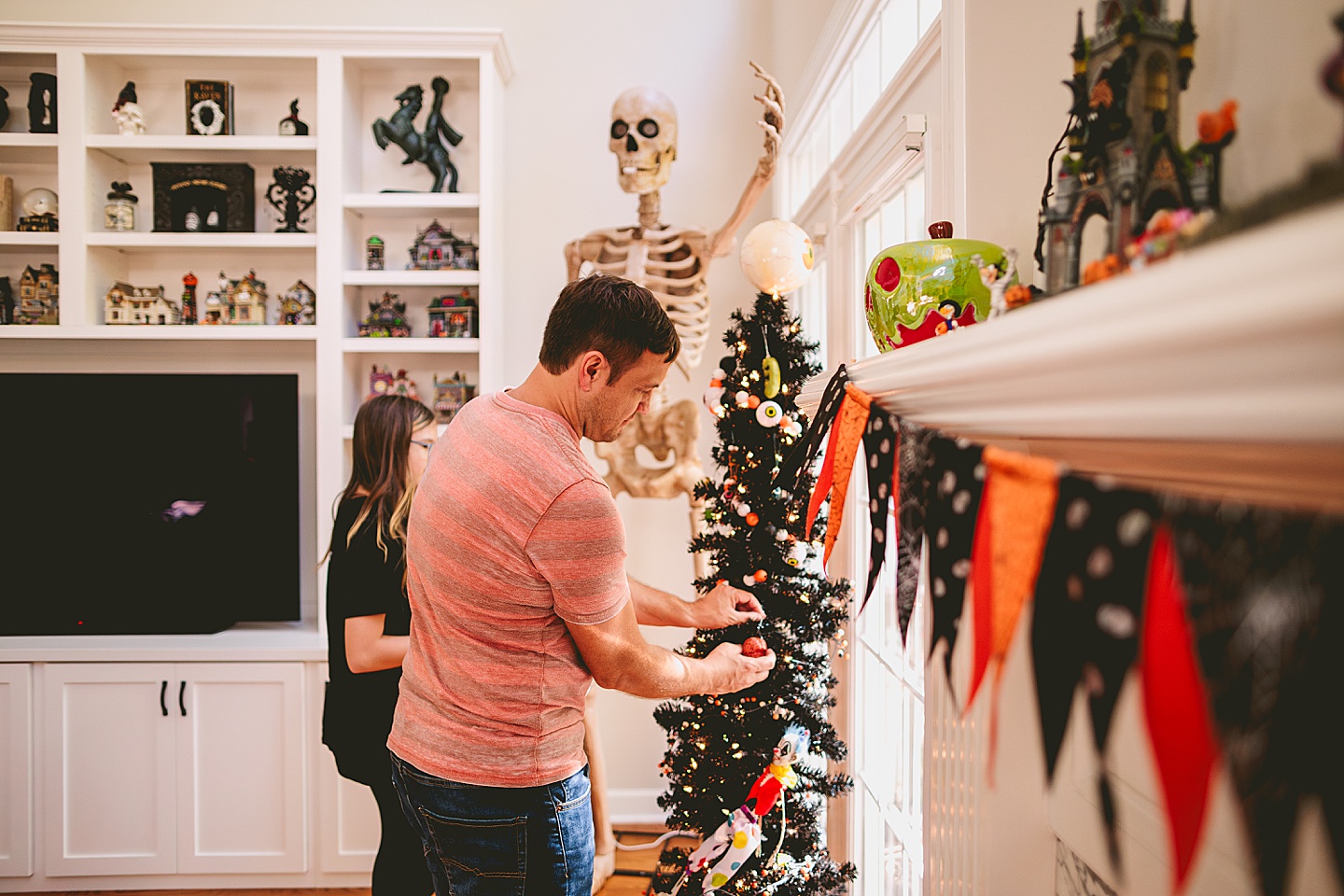 Family decorating black Halloween tree with horror ornaments