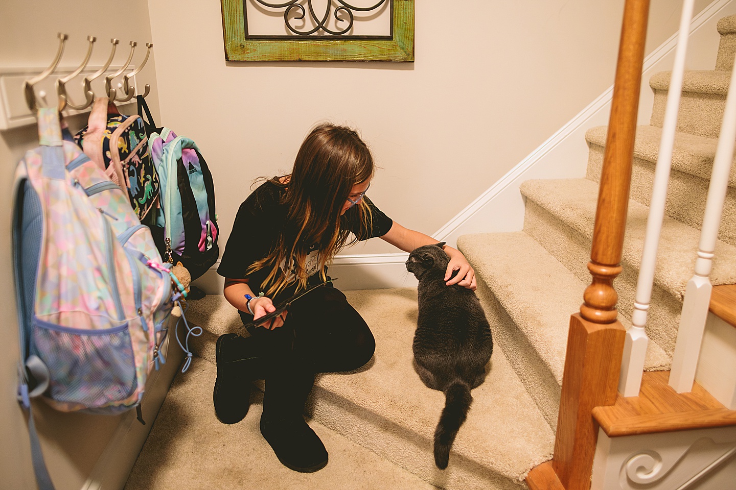 Teenage girl sitting with her arm around cat in stairway