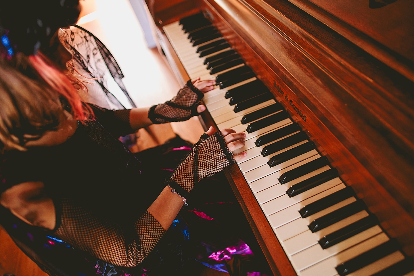 Girl with fishnet gloves for Halloween playing piano
